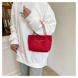 Detail of red canvas handbag with unique colorful beaded handle and gold lettering