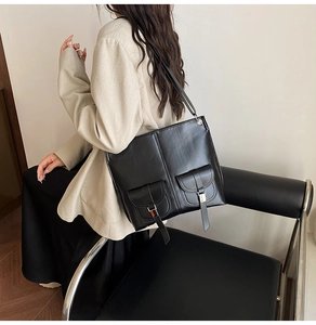 Seitenansicht einer großen schwarzen Shopper-Tasche aus Glanzleder mit funktionalen Taschen