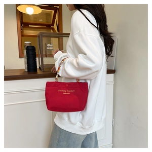 Detail of red nylon tote bag with colorful beaded handle and magnetic closure