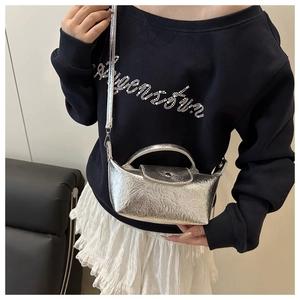 Close-up of a silver metallic textured mini handbag worn with a slim shoulder strap