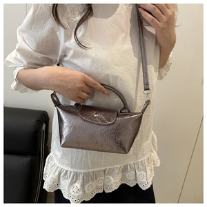 Detail of metallic mini dumpling bag featuring wrinkled texture and round top handle