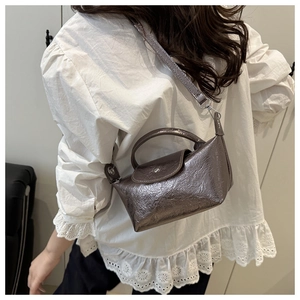 Side view of a silver pleated leather dumpling bag worn on a model's shoulder