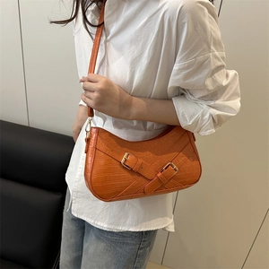 Orange faux crocodile skin underarm bag with metal buckle on a white shirt model