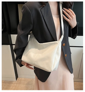 Detail of soft white faux leather hobo bag showing vertical stitching and wide strap
