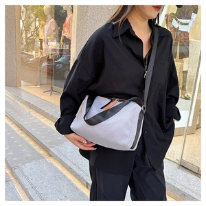 Detail of light grey nylon bag showing black webbing straps and bright orange zipper pull