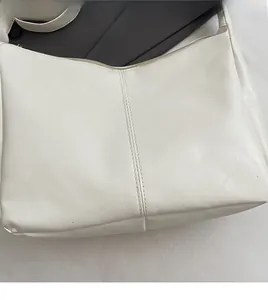 Close-up of cream white faux leather texture and zipper detail on shoulder bag