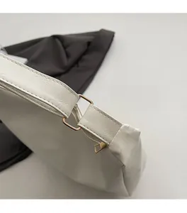 Detail of premium light gold metal hardware and textured cream leather on tote bag