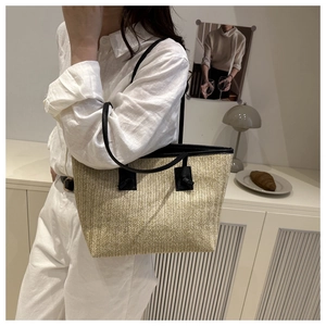 Close-up of woven straw tote bag with black strap and detailed beige wicker texture