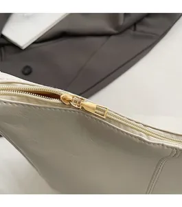 Close-up of smooth gold metal zipper and premium leather texture on white tote bag
