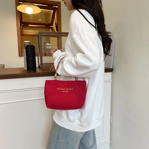 Red canvas handbag with beaded handle and fashion lettering in a lifestyle setting