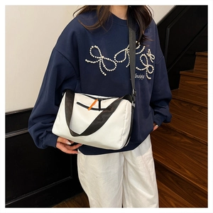 Detail of white nylon shoulder bag with wide black strap and bright orange zipper pull