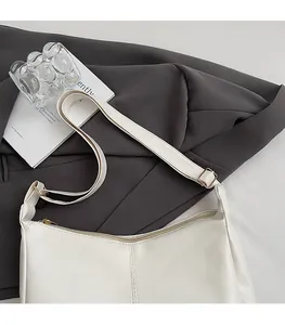 Close-up of white tote bag with fine leather texture, vertical stitching and gold hardware