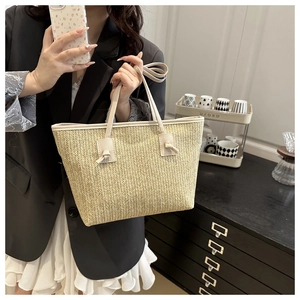 Detail of hand-woven straw tote bag with elegant knotted leather handles and chevron texture