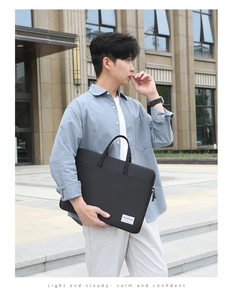 Man carrying a durable black nylon laptop bag with zip closure and minimalist logo