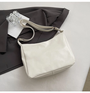 Close-up of a white minimalist shoulder bag with smooth synthetic leather and gold hardware