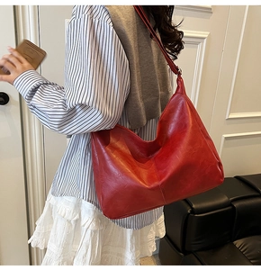 Detail view of large red oil wax leather tote bag worn by a model for daily commuting