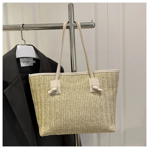 Close-up of beige woven tote bag featuring herringbone texture and faux leather straps