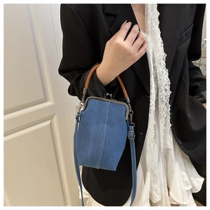 Detail of blue denim crossbody cell phone bag with vintage metal kiss-lock and brown handle