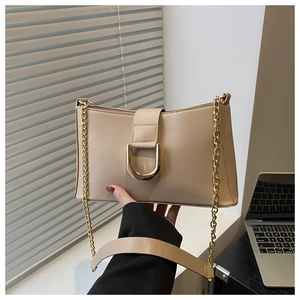 Detail of beige shoulder bag with gold U-shaped metal clasp and chain strap