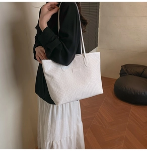 Detailed view of white woven texture on a large faux leather tote bag with shoulder straps