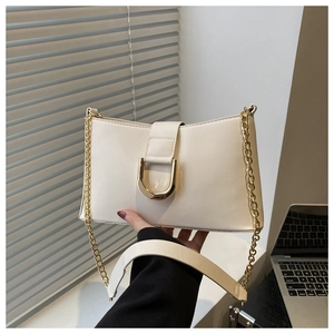 Close-up of cream leather shoulder bag featuring a large gold D-ring buckle and chain strap