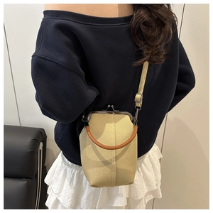 Retro beige canvas bag with metal frame closure and brown leather handle shown on a model