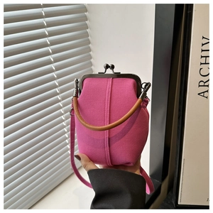 Detail of hot pink textured fabric handbag with vintage metal kiss-lock and brown leather handle