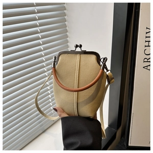Detail of vintage canvas handbag showing top metal clasp and round brown handle