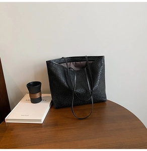 Detailed view of the black woven tote bag texture and long slim double shoulder straps