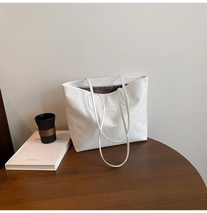 Close-up of white woven tote bag texture with geometric patterns on a wooden table