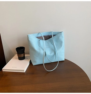 Macro view of light blue checkered woven tote bag with slim shoulder straps