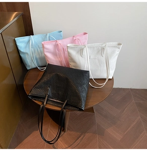 Detail of woven texture tote bags in blue, pink, white, and black on a wooden table