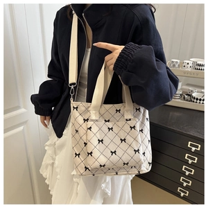 Détail du sac cabas en velours beige avec motif nœuds noirs et bandoulière réglable