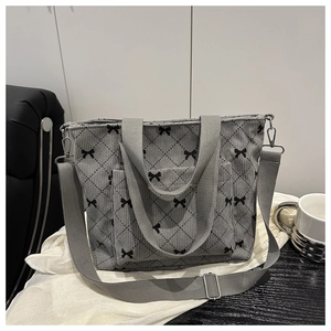 Dettaglio borsa tote in velluto a coste grigio con fiocchi neri e tracolla in tela robusta
