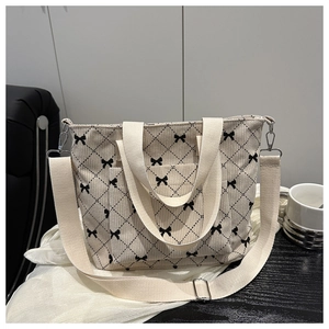 Vista dettagliata della borsa tote in velluto a coste beige con fiocchi neri e rombi