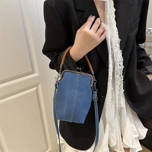Denim-Umhängetasche mit Kussverschluss und Ledergriff an einem schicken Outfit