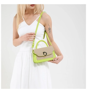 Close-up of green leather and straw crossbody bag with decorative metal D buckle