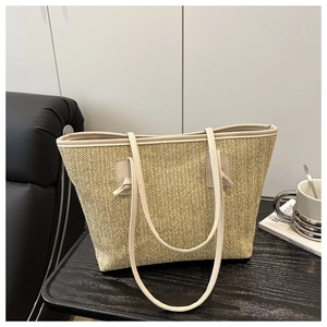 Detail of hand-woven straw tote with chevron texture and knotted cream leather strap