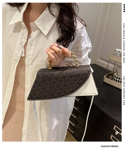 Detail of asymmetrical leopard print handbag with golden spiral chain handle and white strap