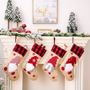 Detail of four burlap Christmas stockings with gnomes and red black plaid cuffs hanging on mantle