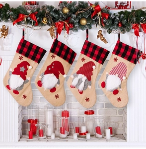 Detailed view of four burlap Christmas stockings with gnome appliques on a white fireplace