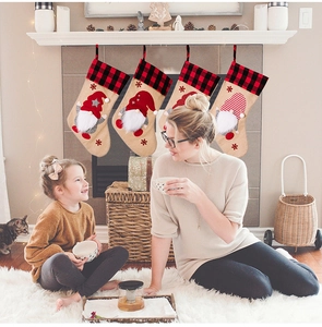 Detailed view of four burlap Christmas stockings with gnome embroidery hanging on a fireplace