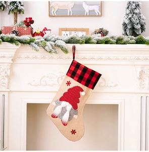 Close-up of burlap Christmas stocking with gnome embroidery and red plaid trim by a fireplace