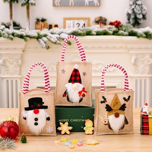 Close-up of burlap Christmas gift bags with gnome embroidery and festive decor