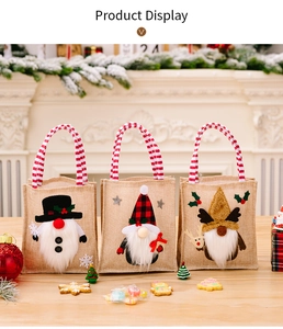 Detailed view of three burlap Christmas gift bags with gnome embroidery on a wooden table