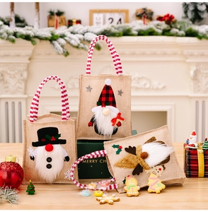 Detailed view of three festive burlap Christmas gnome gift bags on a wooden table