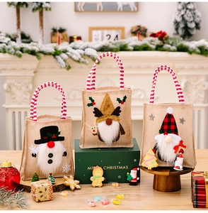 Detailed view of three burlap Christmas gift bags with festive gnome applique and striped handles