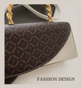Detail of bicolor leather handbag featuring brown monogram pattern and golden metal handle