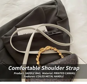 Detail of saddle bag with logo pattern, gold twist handle and adjustable strap