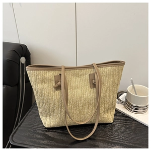 Close-up of beige woven straw tote bag featuring brown PU leather handles and strap details